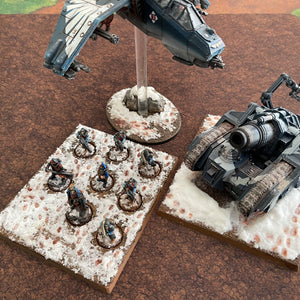 ‘Cracked Earth’ design shown with miniatures for scale purposes 30”x22”’ gaming mat with a Cracked Earth Dirt field theme, marketed for tabletop gaming, accompanied by a black canvas zipper bag TableWar neoprene KillTeam Tournament Tabletop Game mat 